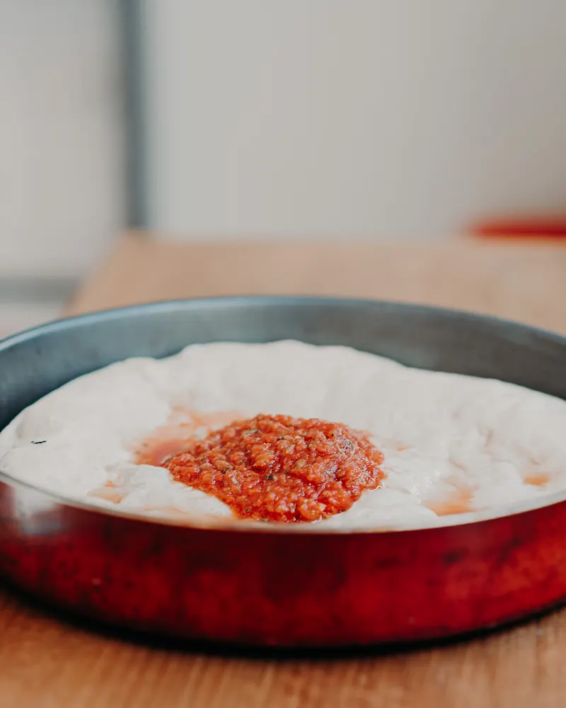 Masa estirada en el molde con la salsa de tomate recién puesta